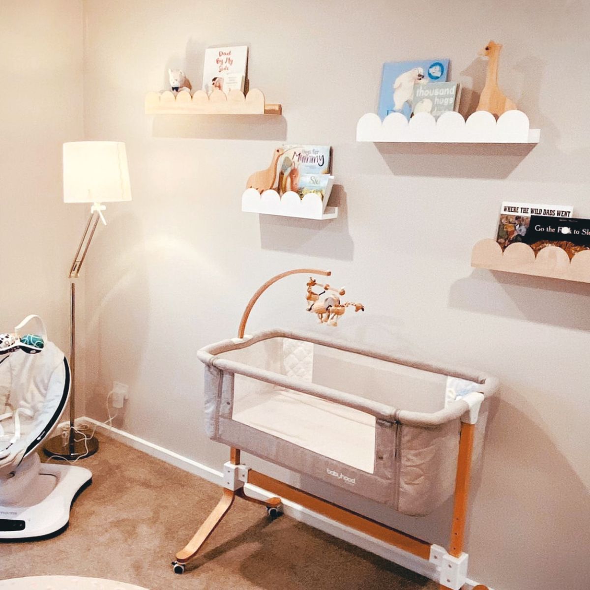 Several arch or scallop bookshelves in raw wood and white is in this baby's nursery room