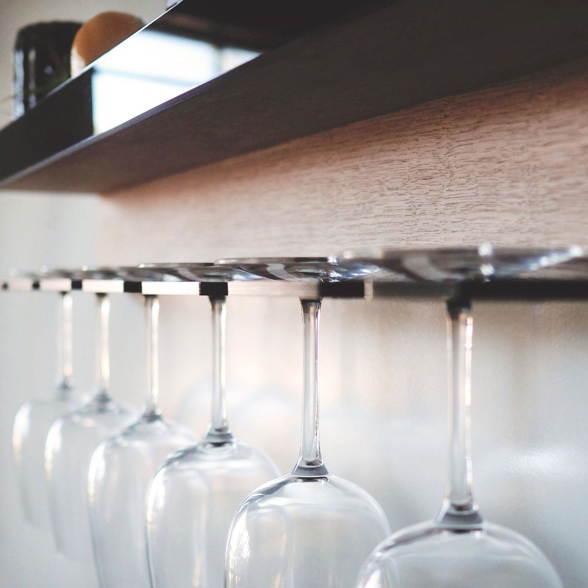 A shelf for wine glasses and wine/alcoholic beverages made from Tasmanian oak with a black acrylic front and holder. This is a close up of the wine glass holder