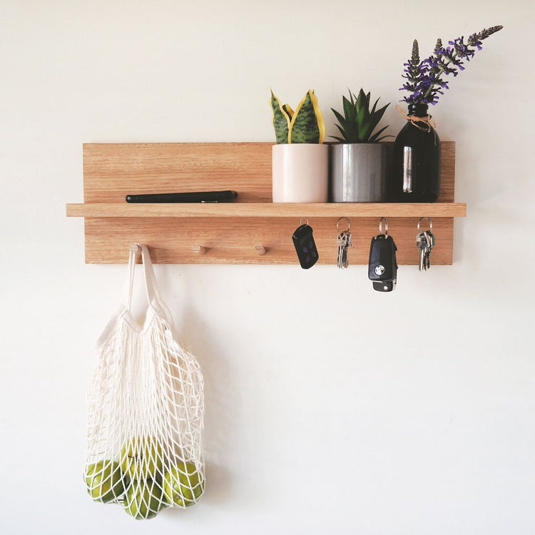 Minimalist wooden entryway shelf organiser mounted on a white wall. 