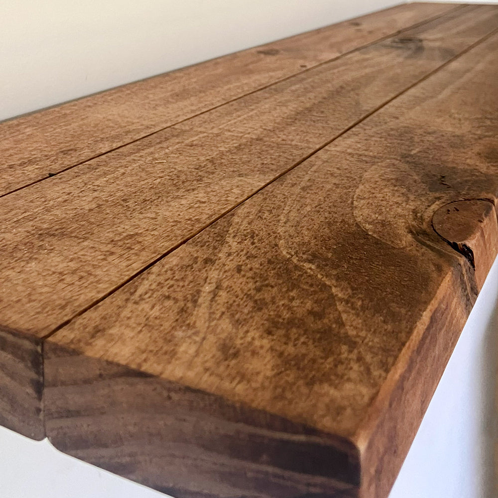 Top close-up view of a rustic walnut brown timber wall ledge highlighting the natural knots, cracks, and rich grain textures of the solid pine wood.
