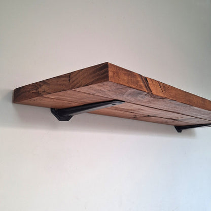 Underneath close-up view of a handcrafted walnut brown pine wood shelf showcasing the heavy-duty black mounting bracket and organic wood grain.