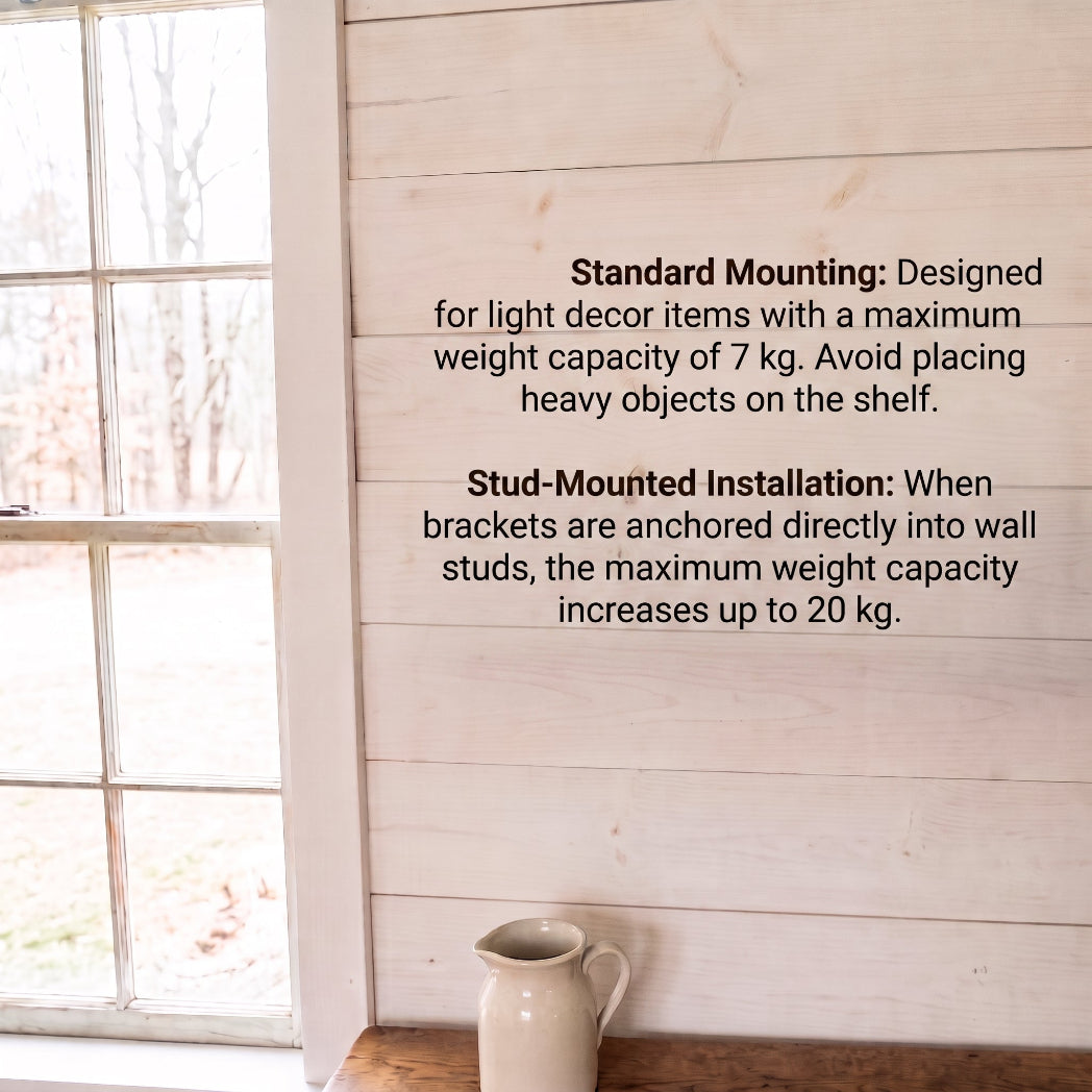 White wood wall with weight capacity instructions for a shelf bracket, next to a window and above a small ceramic pitcher on a wooden surface.