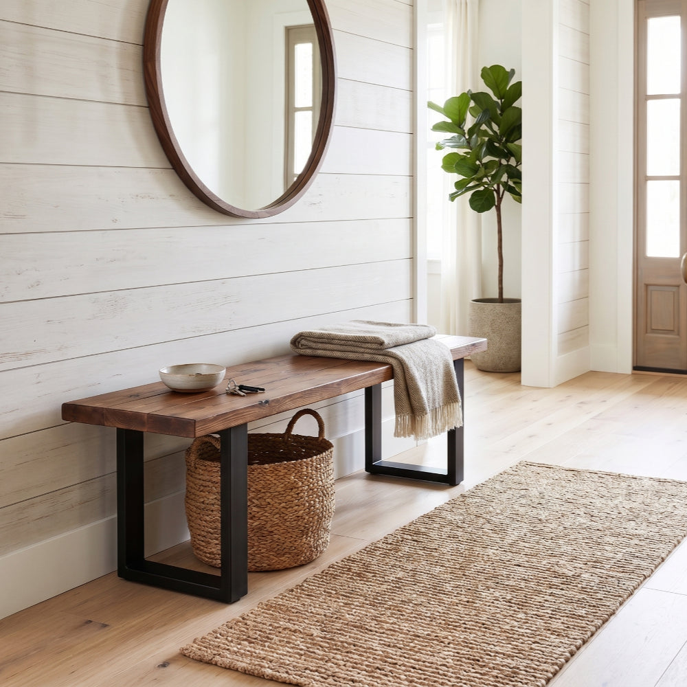 Modern farmhouse entryway featuring a rustic solid wood bench with black metal legs, a matching round wooden mirror on a white shiplap wall, a jute runner rug, and a potted fiddle-leaf fig tree.